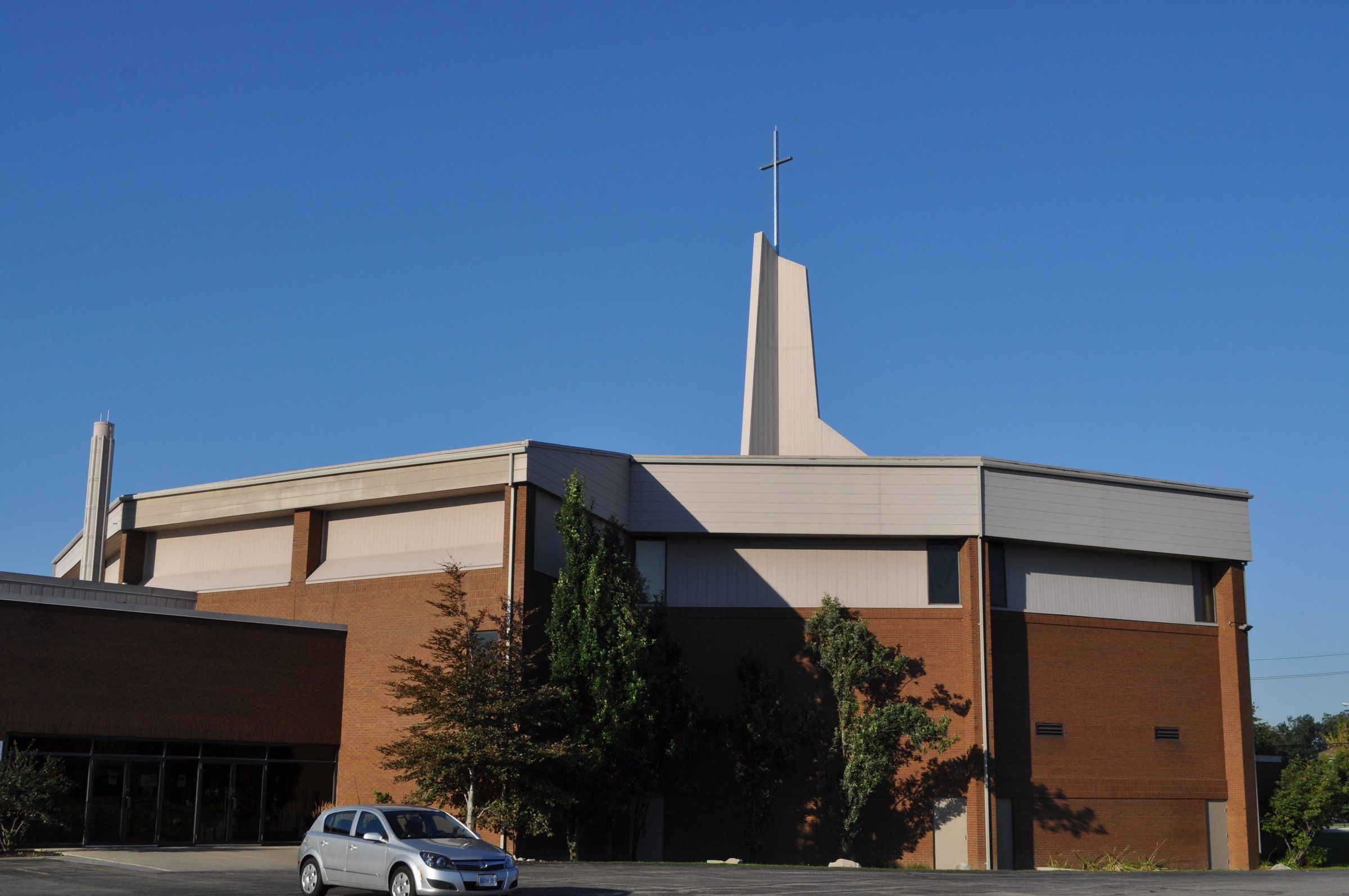 Bethel Gospel Tabernacle, a large modern church of brown brick and pale panels with a tall, slender white tower topped by a cross, beside its parking lot on Upper Wellington Street