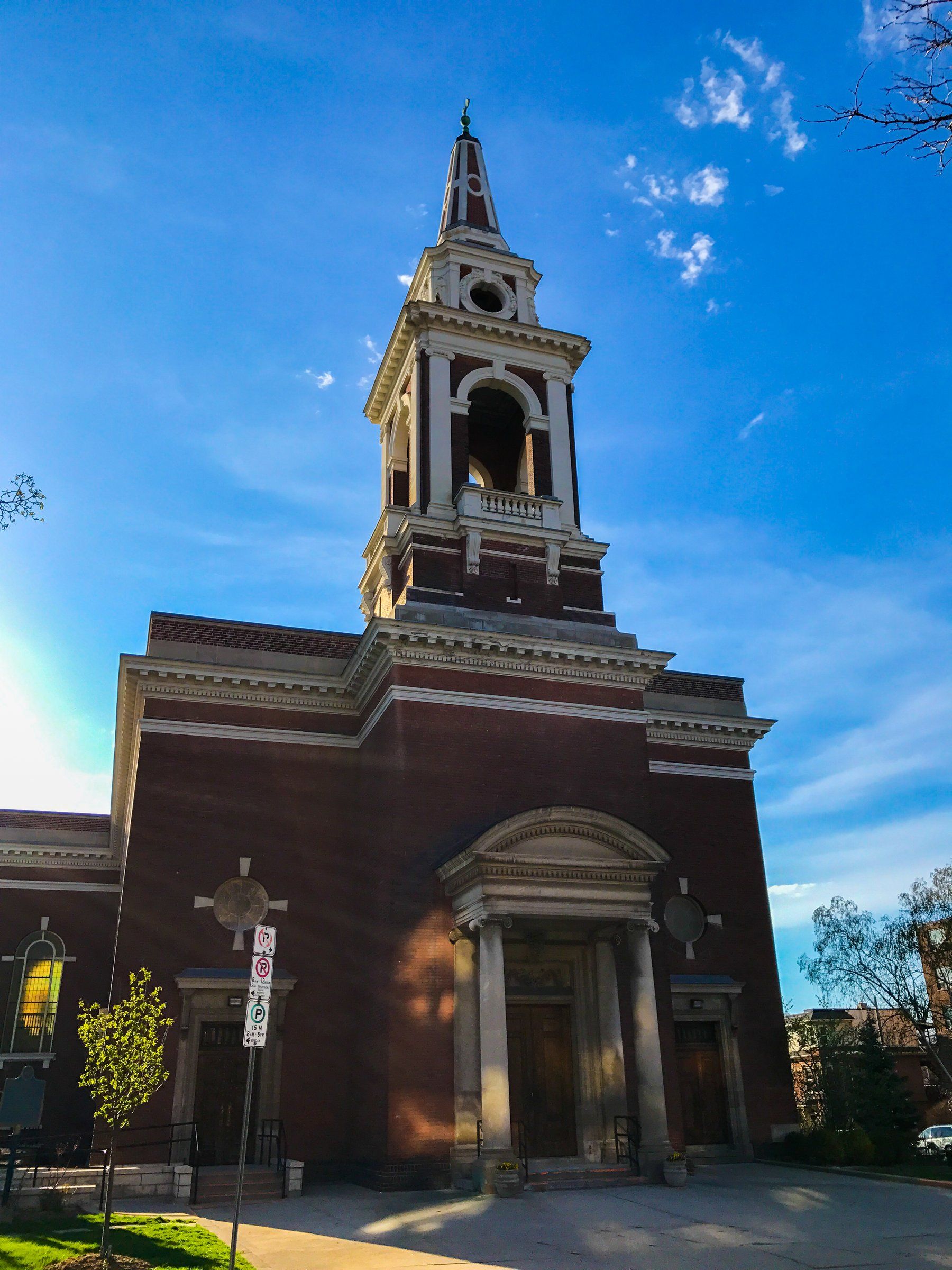 Central Presbyterian Church, a brick church with a columned portico at its door and a tall, tiered bell tower rising above the front, against a blue sky