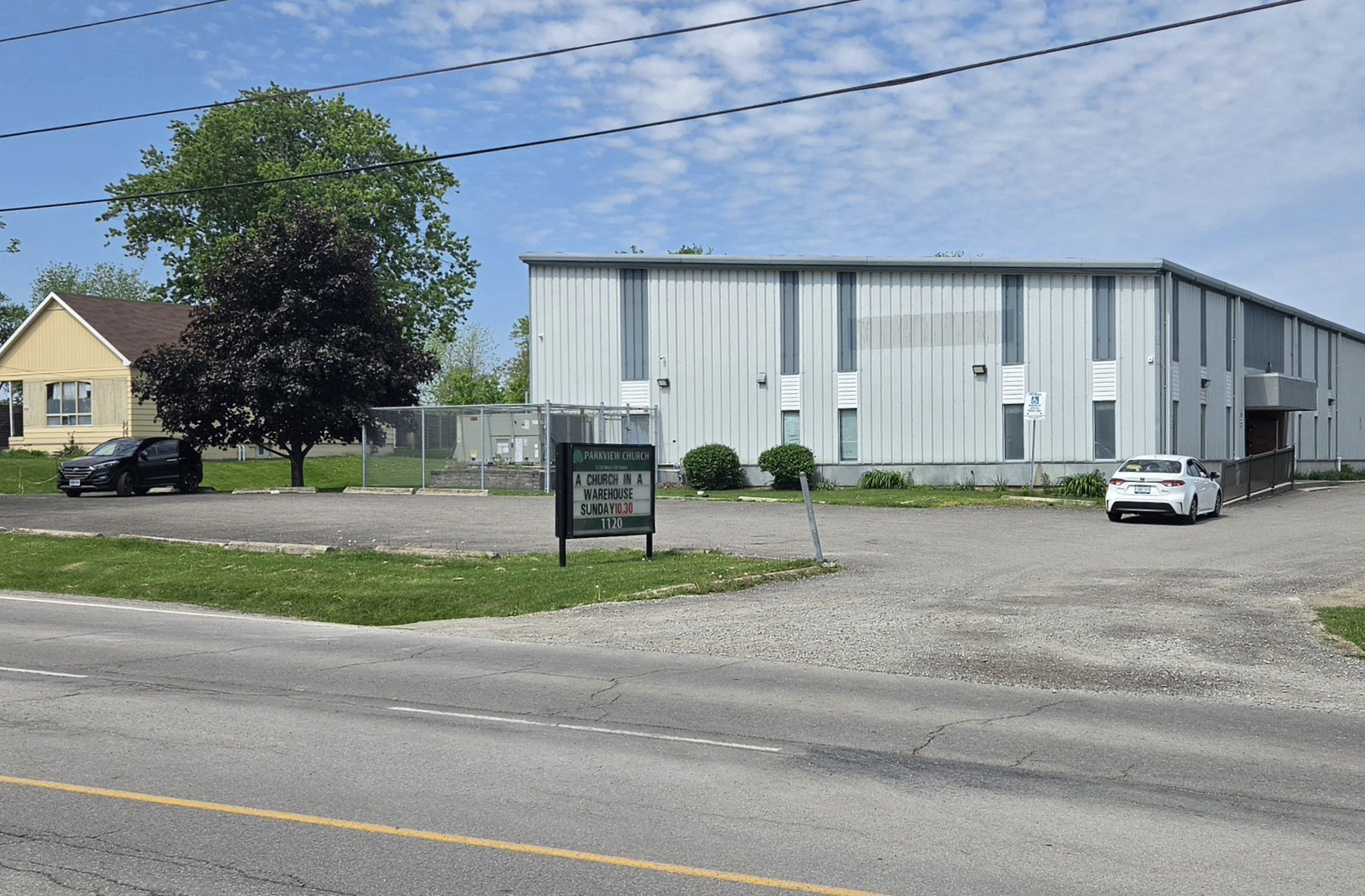Parkview Church, a two-storey warehouse-style building clad in pale grey metal siding with tall narrow windows, behind a parking lot and the church's roadside sign