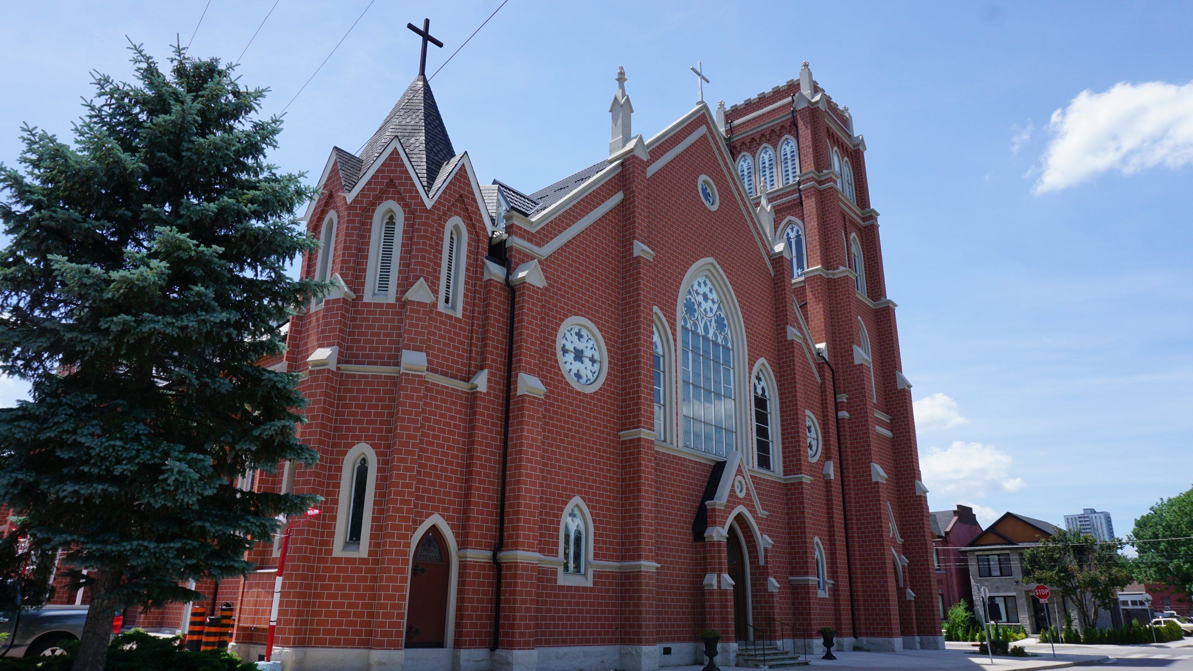 St. Mary's Pro-Cathedral, a red-brick church with pale stone trim, tall pointed windows and a square bell tower, seen from the street beside a large evergreen