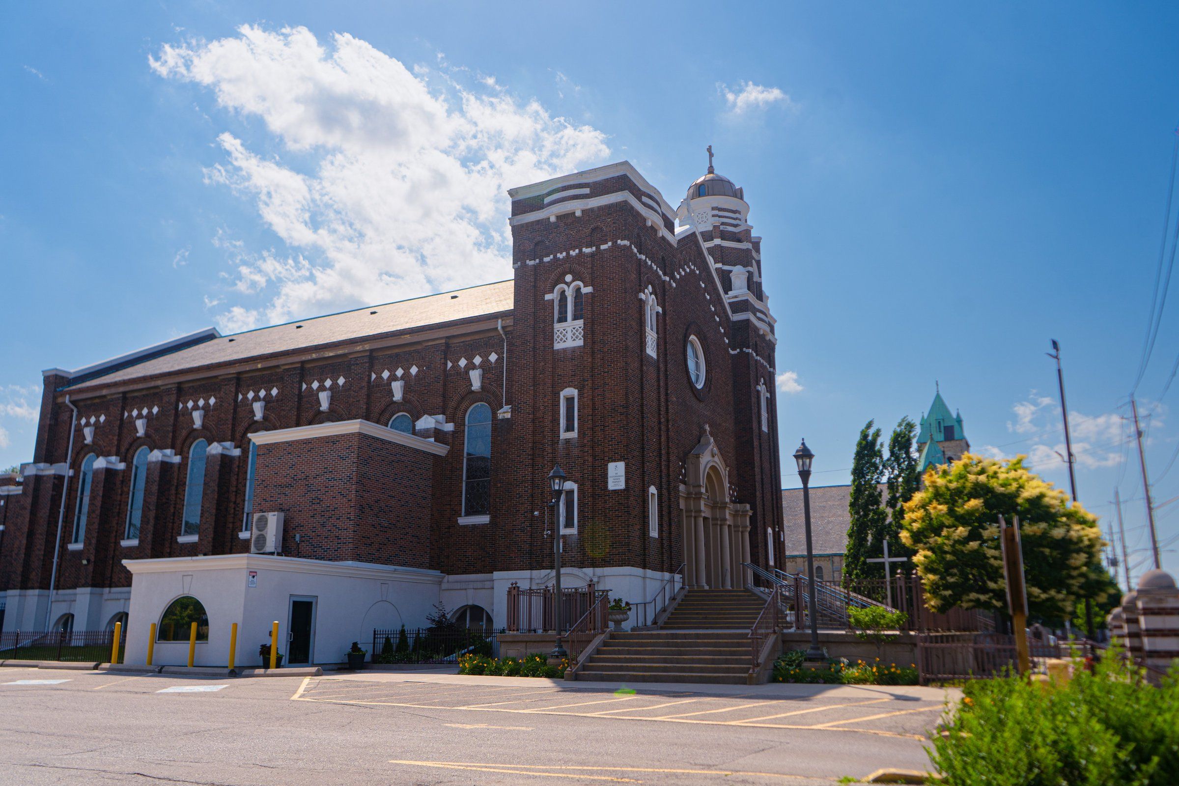 St. Stanislaus Kostka Church, a dark red-brick church with white trim, a square tower and a taller domed tower above a broad flight of steps, seen across a parking lot